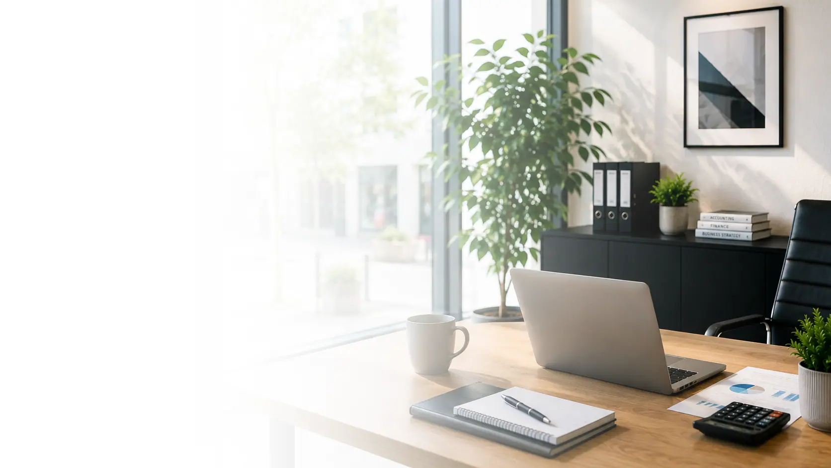 A tidy office desk with a laptop, notebook and calculator